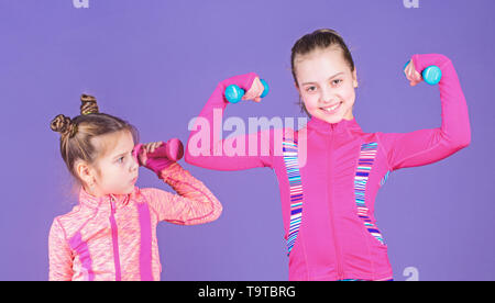 Girls cute kid exercising with dumbbells. Motivation and sport example concept. Toddler repeat exercise after sister. Sport exercises for kids. Health Stock Photo