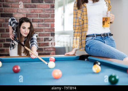 Two female students playing billiard game and drinking beer. Stock Photo