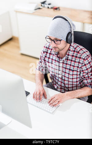 Modern programmer with headphones working on his computer. Stock Photo