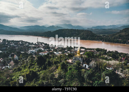 Luang Prabang, Laos. Aerial view of Luang Prabang town in Laos. Cloudy sky over small city surrounded by mountains. Mekong river Stock Photo