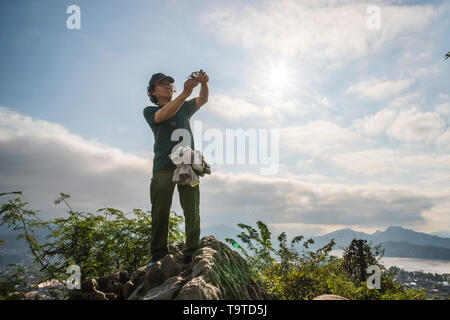 Luang Prabang, Laos - 14 January 2019. tourist bought a small bird in a cage, to free on top of Mount Phousi as an omen for good fortune. Guy man lets Stock Photo