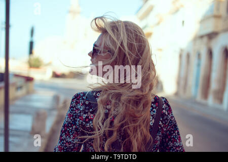 Young stylish confident blonde woman walking on street rear view Stock Photo