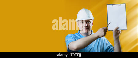bald brutal man Builder in a white helmet on a yellow background Stock Photo