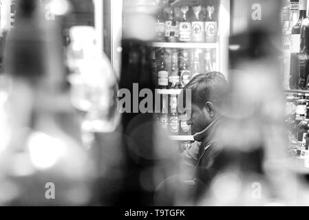 man sitting  among bottles with bokeh, in black and white Stock Photo