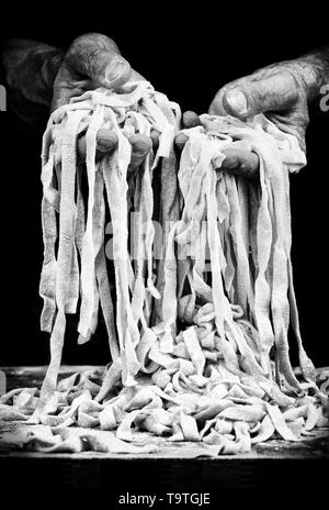 Hands of man and handmade fettuccine in black and white Stock Photo