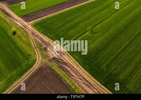 Aerial view of dirt road through countryside and agricultural field from drone pov Stock Photo