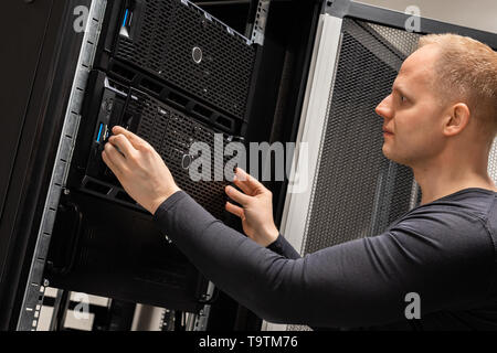 IT Professional Working With Servers In Large Datacenter Stock Photo