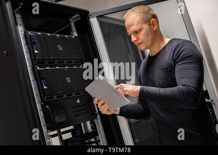 IT Engineer Holding Digital Tablet Analyzing Servers in Datacenter Stock Photo