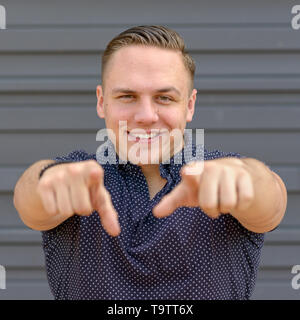 Smiling happy young man gesturing pointing to the camera with both hands in a square Format with copy space Stock Photo