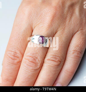 Silver ring with ruby star gemstone caboshon on female hand Stock Photo