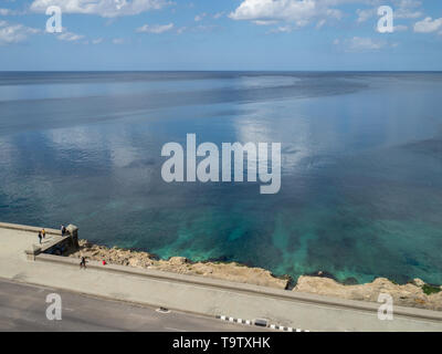 In Havana, Cuba, people relax on the seafront promenade by a clear, calm Atlantic Ocean Stock Photo