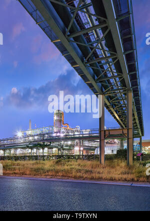 Scaffold with pipeline and Illuminated petrochemical production plant at twilight at Port of Antwerp. Stock Photo