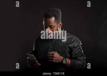 Indoor shot of impressed and amazed attractive African American man with beard and short haircut, holding smartphone, looking surprised at gadget scre Stock Photo