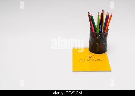 yellow notepad with pencils in a basket on white background, isolated. back to school. great ideas Stock Photo