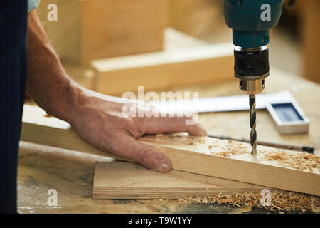 Closeup of unrecognizable carpenter drilling wood while working in joinery, copy space Stock Photo