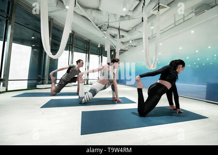 Women and man holding their foot while stretching doing yoga Stock Photo