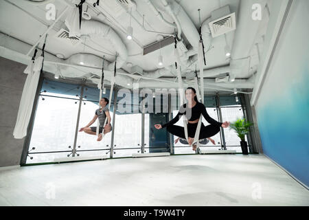 Women and man feeling amazing while doing flying yoga Stock Photo