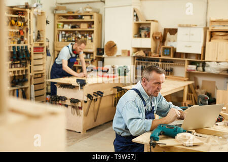 High angle portrait of two carpenters working with wood standing at tables in workshop, copy space Stock Photo