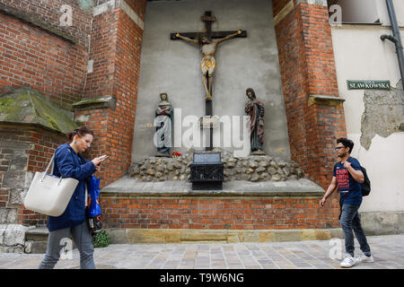 People seen walking past a church wall with a Jesus Christ&rsquo;s 