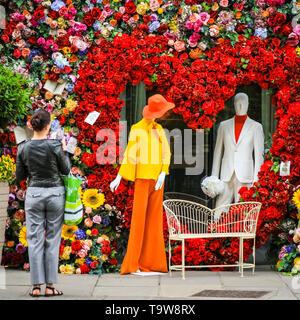 Belgravia, London, UK, 20th May 2019. People take snaps of the display. The Hari Hotel has created a spectacular heart shaped floral display with sixties inspired figures and a love seat, which is popular with passers-by taking photos. Credit: Imageplotter/Alamy Live News Stock Photo