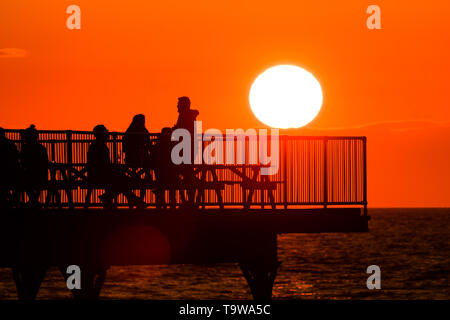 Aberystwyth Wales UK, Monday 20 May 2019  UK Weather: People  on the pier enjoying  a drink and the view of the glorious golden sunset over Cardigan Bay, at the end of a day of warm spring sunshine in Aberystwyth Wales. The weather is set fine for the coming days , with extended spells of warm sunshine  photo credit: Keith Morris / Alamy Live News Stock Photo