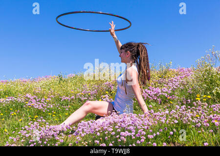 Southbourne, Bournemouth, Dorset, UK. 21st May, 2019. UK weather: lovely warm sunny morning as Lottie Lucid performs her hula hooping routine on the seafront cliffs at Southbourne among the wildflowers, Sea Thrift, Armeria maritime, enjoying the warm sunny weather in her mini dress. Credit: Carolyn Jenkins/Alamy Live News