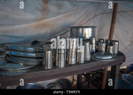 Close up of steel utensils bowls, pots and trays used by an old open kitchen restaurant in India Stock Photo