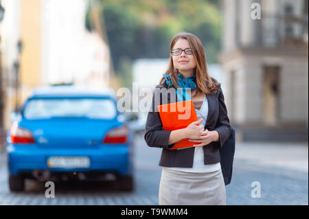 Portrait of happy smiling business woman with red folder in city Stock Photo