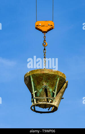 GARDA, LAKE GARDA, ITALY - SEPTEMBER 2018: Tower crane lowering a heavy steel bucket of concrete on a building site in the town of Garda on Lake Garda Stock Photo