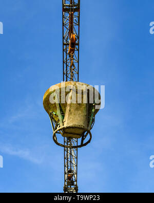 GARDA, LAKE GARDA, ITALY - SEPTEMBER 2018: Tower crane lowering a heavy steel bucket of concrete on a building site in the town of Garda on Lake Garda Stock Photo