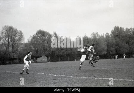 1950s, historical, amateur football match, picture shows two players in the kit of the era, long, baggy shorts, long-sleeved shirts and ankle-high boots competing in the air for the ball, England, UK. Stock Photo
