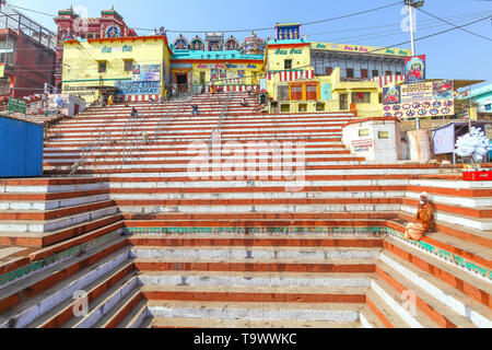 Ancient Hindu temple at Varanasi India with long steep staircase. Hindu monk sadhu sitting on the stairs of the temple Stock Photo
