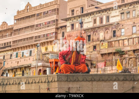 Sadhu baba sitting at Varanasi Ganges ghat with ancient architecture building at the backdrop. Stock Photo