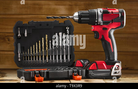 Cordless drill driver in red with rubberized handle in profile with drill bits set Stock Photo