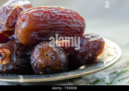 Dried dates  in a bowl on rustic embroidered cover,  close up. Stock Photo