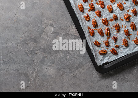 Baking sheet with candied pecan nuts on grey background Stock Photo - Alamy