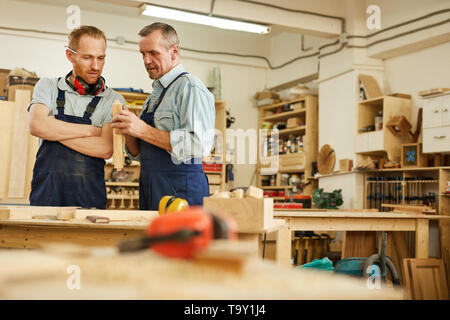 Waist up portrait of senior carpenter teaching apprentice  while working  in joinery workshop, copy space Stock Photo