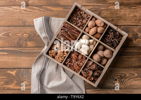 Assortment of nuts and spices in divided box on wooden table Stock Photo