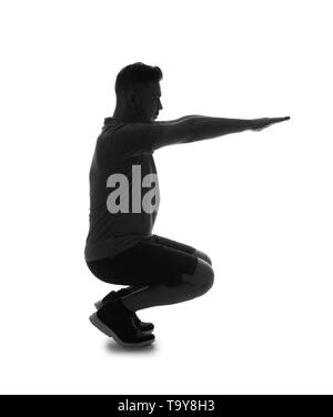 Silhouette of sporty man doing a squats on white background Stock Photo