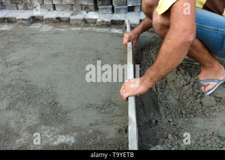 The worker aligns the foundation for the final laying of the paving slab on the sidewalk Stock Photo