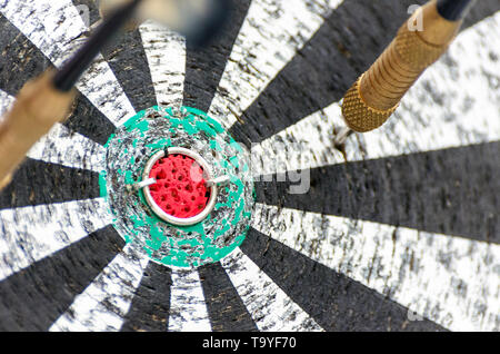 Darts Missing Bullseye on a Worn Out Dartboard. Proper Targeting, Losing Concept. Stock Photo
