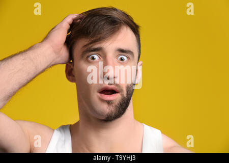 Shocked man having half of his face shaved against color background Stock Photo