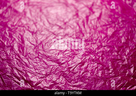 crumpled plastic pink polyethilene film abstract background with selective focus. Stock Photo
