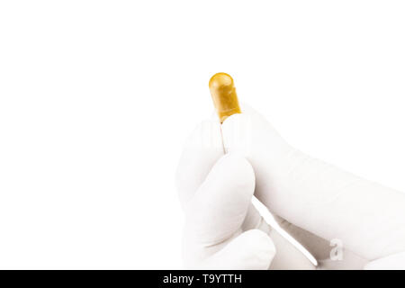 hand in medical glove holding organic med capsule isolated on white background closeup. Stock Photo