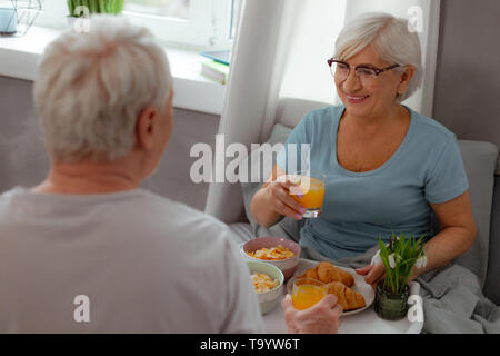 Glowing wife having juice and cereals breakfast with her spouse Stock Photo