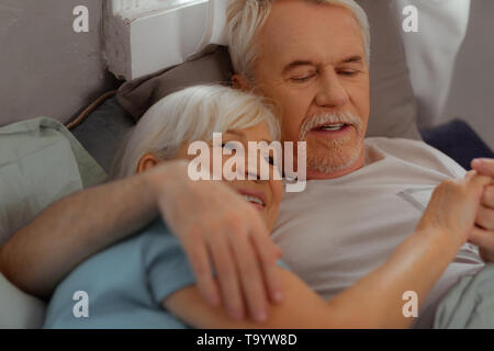 Happy couple in advanced years lying and hugging each other Stock Photo