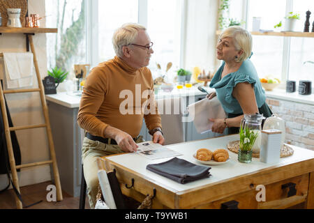 Stylish well-dressed white-haired couple discussing menu for a romantic evening. Stock Photo