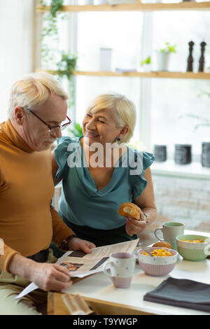 Beaming spouses enjoying breakfast and conversation at the kitchen Stock Photo