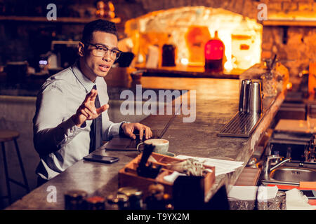 Freelancer working on laptop ordering drink at the bar stand Stock Photo