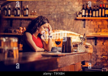 Woman having headache while waiting for man in bar Stock Photo